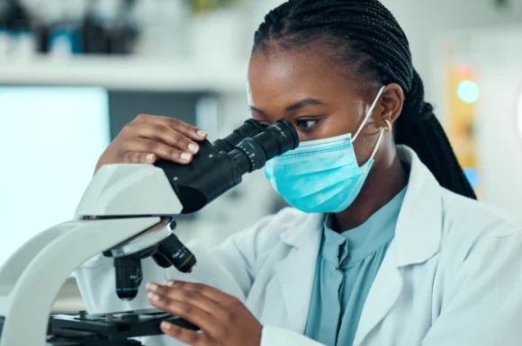 Kenyan female researcher using a microscope at CRK-NGO clinical research site