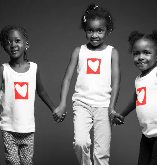 Four children holding hands wearing heart-logo shirts, symbolizing unity and pediatric heart surgery support.