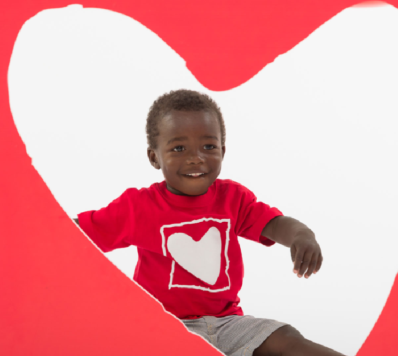 Smiling child in red shirt with heart symbol representing CRK-NGO Saving Children’s Hearts program-Children’s Heart Surgery Kenya